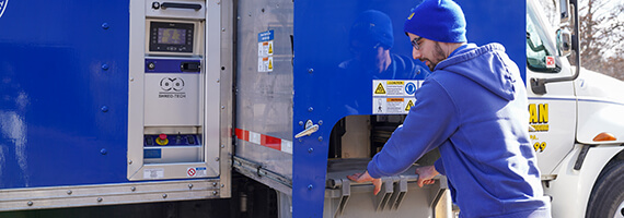 TITAN Mobile Shredding truck driver loading shred bin on truck