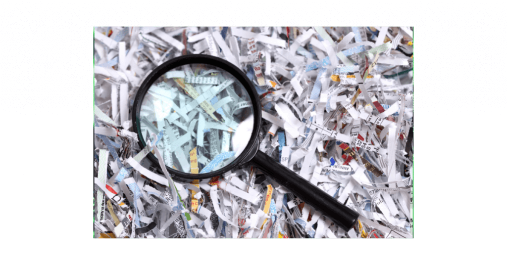 Magnifying glass on pile of shredded documents