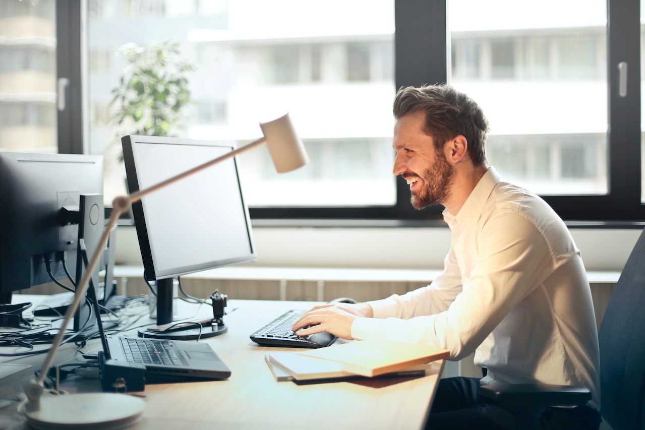 a man sitting at a desk and looking at a computer.