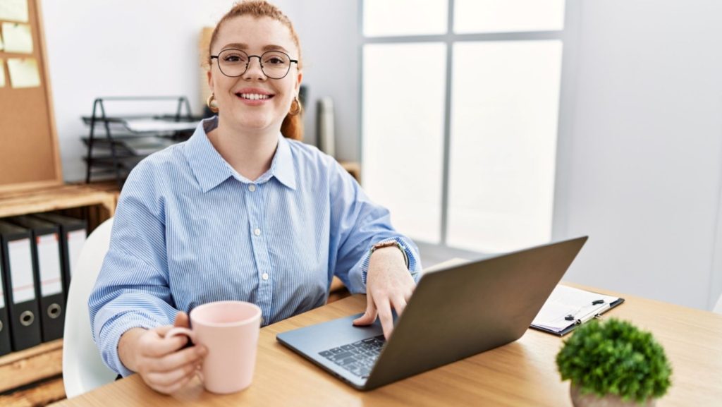Office worker at desk with laptop and drink