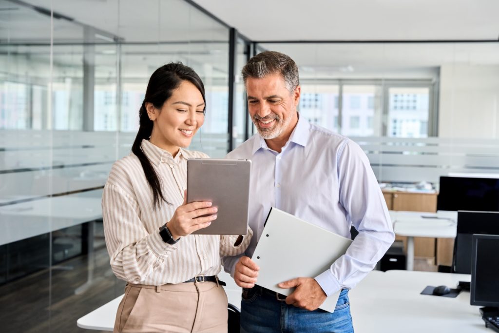 Two office workers looking at paperwork smiling