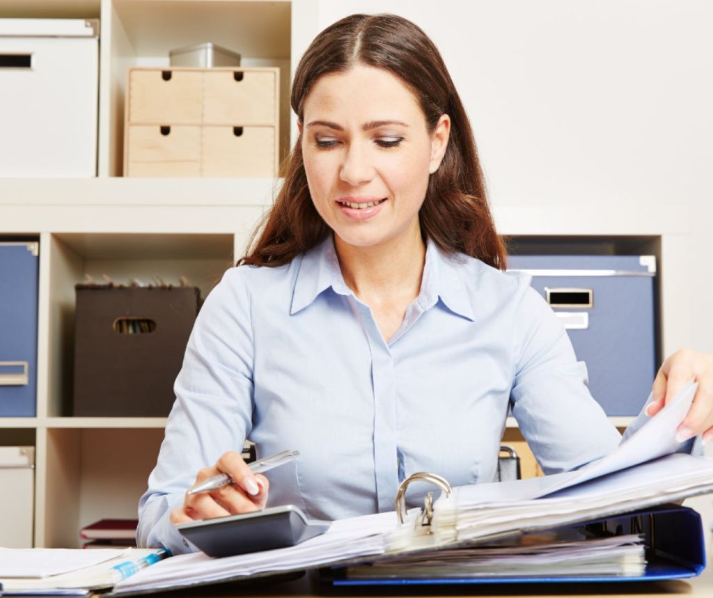 An image of a woman seated at a desk with documents.