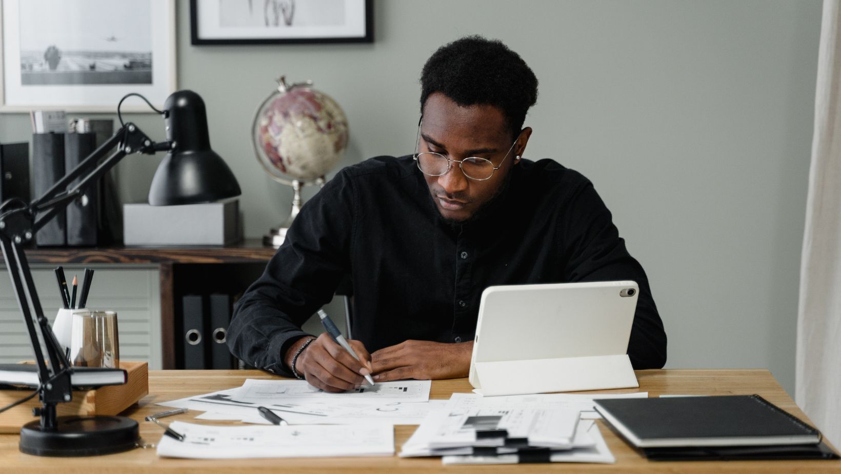 man writing on paper with pen in a home office