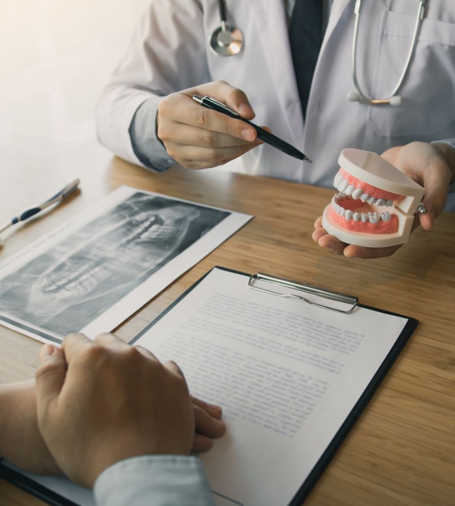dentist holding pen pointing to the dentures and is describing the problem of teeth